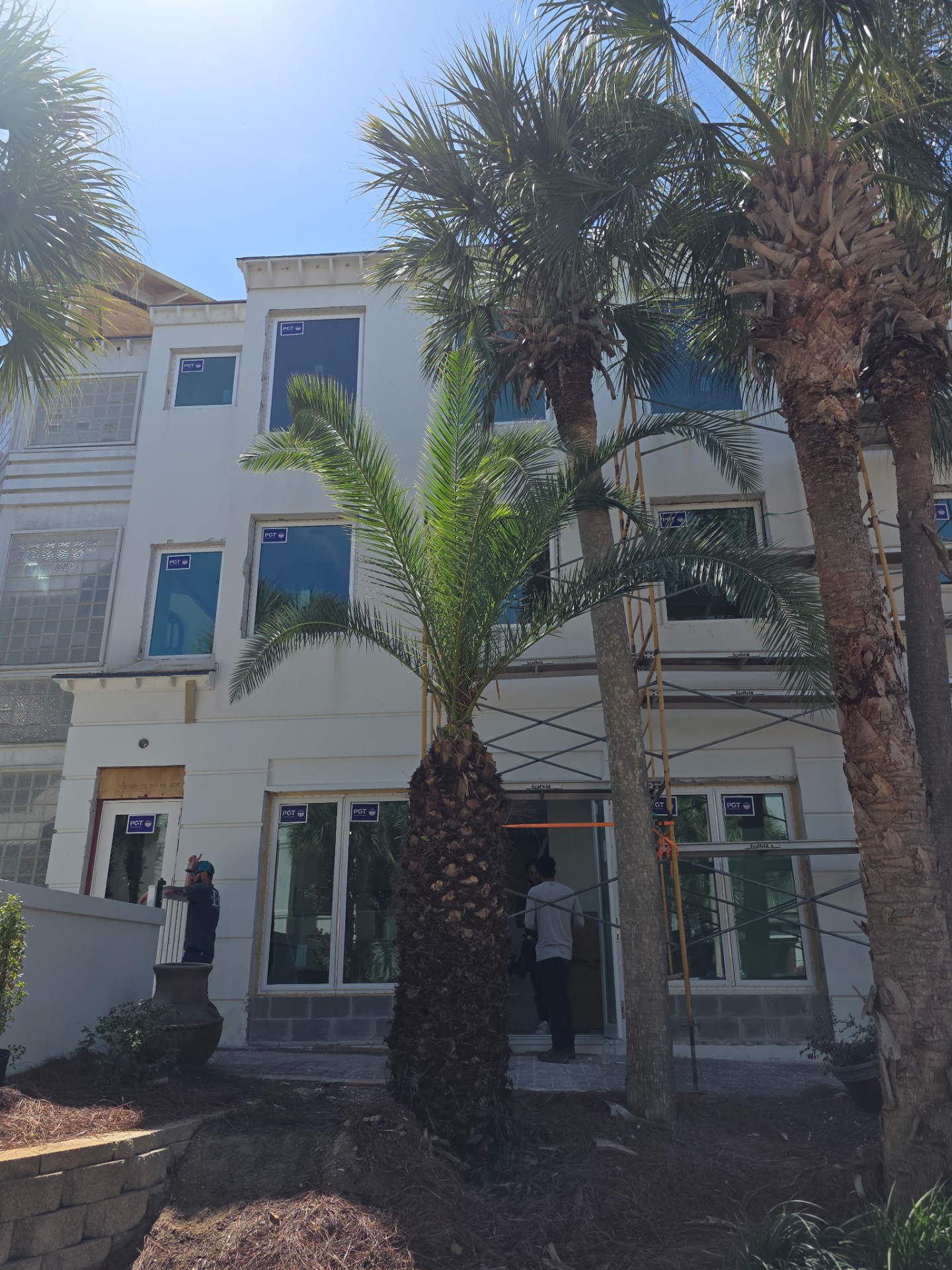Three-story stucco home with new impact windows being installed
